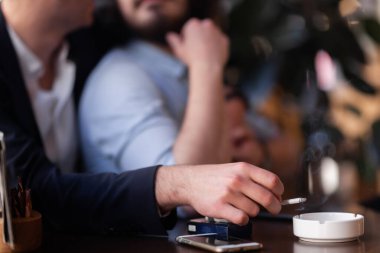 İki arkadaş bir kafede sarılıyorlar, sigara içiyorlar..