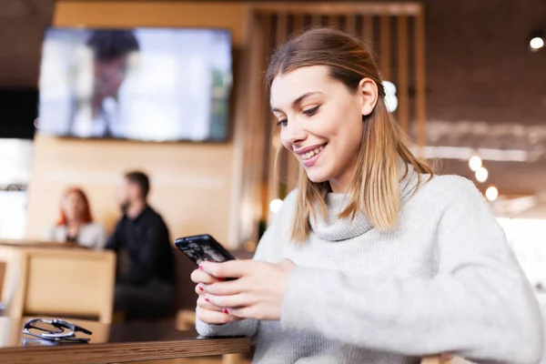 Modern Bir Kafede Telefona Bakan Bir Kız Gülümsüyor — Stok fotoğraf