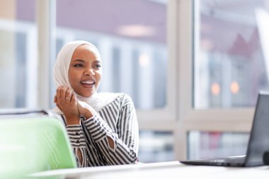 Ofiste dizüstü bilgisayarla çalışan Afrikalı Müslüman bir kız..