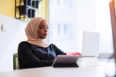 Ofiste dizüstü bilgisayarla çalışan Afrikalı Müslüman bir kız..