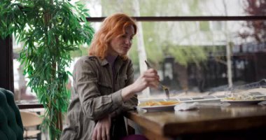 Bir kafede, kızıl saçlı bir kadın pencerenin yanında oturur. O bir aperatif yemeyi bitirdi ve şimdi yemeğinin parasını ödüyor. Gündüz vakti pencerenin dışında bir ağaç görünür..