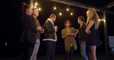 Arkadaşlar geceleri dışarıda toplanır, içkinin tadını çıkarır ve sıcacık iplik ışıkları altında sohbet ederler..