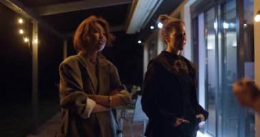 İki genç kadın gece açık hava partisinde fikirleri tartışıyor ve tasarlıyorlar. Yumuşak, sıcak ışık rahat bir atmosfer yaratır..