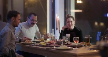 Arkadaşlar bir masanın etrafında toplanır, sıcak, mum ışığında yemek, içki ve kahkahaların tadını çıkarırlar..