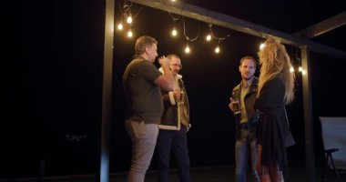 Arkadaşlar geceleri terasta içki içip sohbet etmekten zevk alıyorlar. Sıcak telli ışıklar sıcak ve davetkar bir atmosfer yaratır..