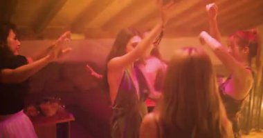 Genç kadınlar renkli disko ışıkları altında dans edip parti yapıyorlar. Arkadaşlar coşkulu bir ev partisinde ya da gece kulübünde kutlama yapıp eğleniyorlar..