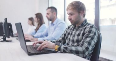 Ofisteki insanlar dizüstü bilgisayarlar ve bilgisayarlar üzerinde çalışıyorlar. İş arkadaşları takımı. Saha videosunun derinliği. Sağ kamera hareketi.