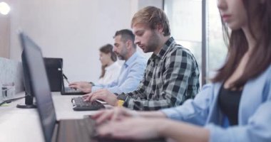 Ofisteki insanlar dizüstü bilgisayarlar ve bilgisayarlar üzerinde çalışıyorlar. İş arkadaşları takımı. Saha videosunun derinliği. Kamera hareketini ileri al.