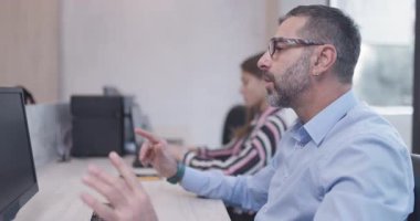 Bir iş adamı ofiste iş arkadaşlarıyla konuşur. Meselesini iş arkadaşlarına göstermek için elleriyle el kol hareketi yapıyor..