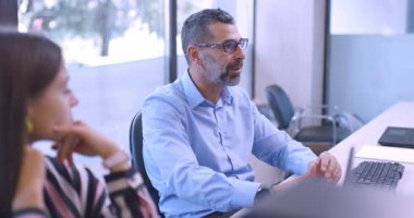 İş adamı, ofisteki bir iş kadınına bir şey açıklar. Bir proje hakkında konuşuyorlar..