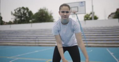 Açık havada antrenman yapan genç bir bayan basketbolcu odak ve atletizm sergiliyor. Kendini adamış ve takım çalışmasıyla bir oyuna hazırlanıyor..