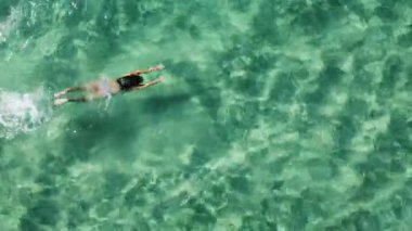Güzel turkuaz suda yüzen bir kadın. Havadan görünüşlü. Yaz tatili kavramı.