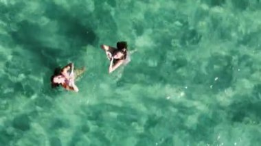 Elleriyle kalp yapan iki kadın güzel, berrak turkuaz suda yüzüyorlar..
