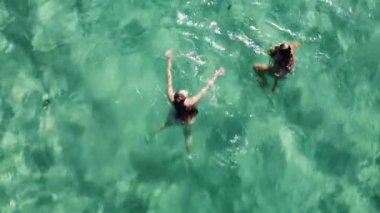 İki kadın güzel turkuaz tropikal suda yüzmekten zevk alır. Yaz tatilindeki dostların hava görüntüsü.