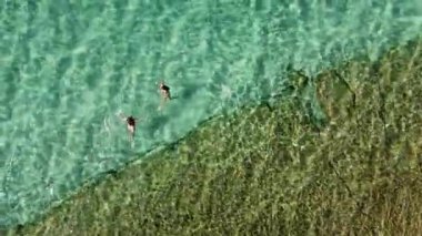 İki kadın Akdeniz 'in berrak turkuaz sularının tadını çıkarıyor. Yaz tatilindeki dostların havadan görünüşü.