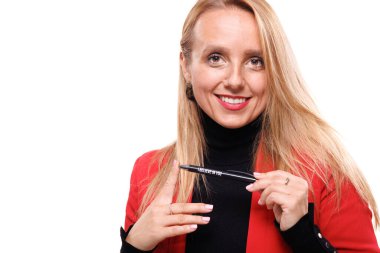 Kendine güvenen bir iş kadını, şık bir ceket giyip, elinde kalemle stüdyoda poz veriyor, profesyonelliği somutlaştırıyor ve arka planda parlak bir gülümsemeyle duruyor..