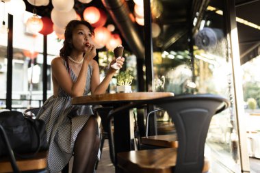 Güzel bir kafede renkli fenerlerle dondurmanın tadını çıkaran genç bir kadın rahatlatıcı ve hoşgörülü bir ruh hali yaratıyor..