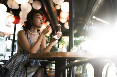 Moda bir kafede dondurmanın tadını çıkaran rahat genç bir kadın şık bir ortamda keyif ve keyif anları yakalıyor..