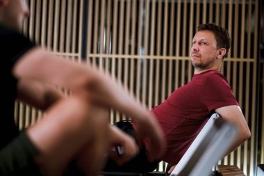 İki birey çağdaş bir fitness stüdyosunda pilates antrenmanına odaklanıyor. Eğitmen, öğleden sonraki oturumda bir katılımcıya yardımcı olur..
