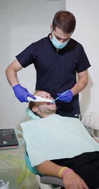 Bir dişçi yüksek teknoloji diş muayenehanesindeki bir hastaya 3 boyutlu diş taraması yapar, ileri teknoloji ve oral sağlık tedavileri için profesyonel bakımı vurgular..