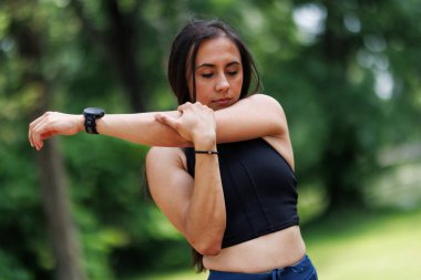 Bir kadın, yemyeşil bir ortamda spor yaparken kollarını uzatır ve egzersiz rutinine odaklanır. Kondisyon uygunluğu ve aktif yaşam tarzına..