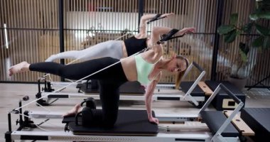 Çağdaş bir fitness stüdyosunda iki kadın antrenman sırasında güç, esneklik ve çekirdek istikrara odaklanıyor..