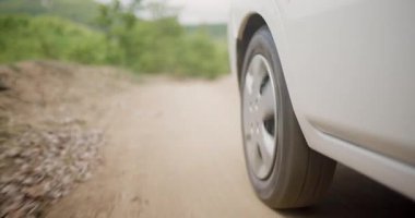 Toprak bir yolda hareket eden bir SUV lastiğinin yakın görüntüsü macerayı, keşfi ve doğadaki off-road yolculuklarını simgeliyor..