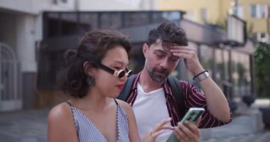 İki neşeli arkadaş dışarıda durup canlı bir şehir atmosferinde telefona bakarken beşlik çakıyor..