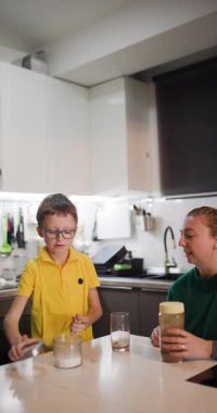 Genç bir çocuk annesi izlerken mutfak lavabosunda bir bardak yıkıyor. Çocuklara sorumluluk ve yaşam becerileri öğretiyorum..