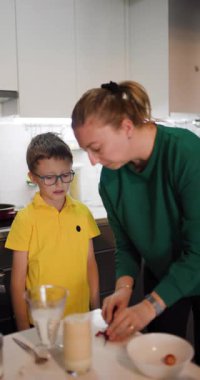 Bir anne ve oğul, modern mutfaklarında birlikte sağlıklı bir kahvaltı kokteyli hazırlıyorlar. Bu sahnede aile bağları ve sağlıklı yeme alışkanlıkları vurgulanıyor..