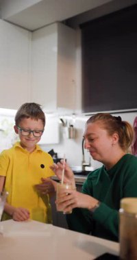 Bir anne ve oğul birlikte milkshake yapıp içerken mutfakta güzel bir anı paylaşıyorlar..