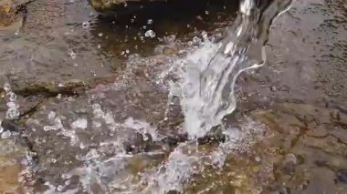 Kayaların üzerinden akan bir nehir kaynağından akan suyun ferahlatıcı sesini hissedin. Damlacıklar ve doğal bir ortamda sakin bir atmosfer yaratıyor..