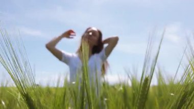Parlak bir çayırda, güneş ışığının tadını çıkararak uzun yeşil çimlerin arasında neşeli bir şekilde duran bir insan. Bereketli manzarası sakin ve doğa ile bir bağ kuruyor. Açık havada neşeli bir anı vurguluyor..