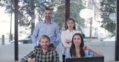 Dört kişilik bir iş ekibi modern ofislerinde başarıyı kutluyor. Zafer için kollarını kaldırdıklarında sevinçleri ve başarıları çok açık..