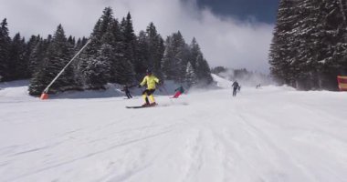 Kayakçılar karlı yamaçlarda ustalıkla dolaşır, dağlarda parlak bir günde yeteneklerini sergilerler. Taze toz kış aktivitelerine heyecan verici bir unsur ekliyor..