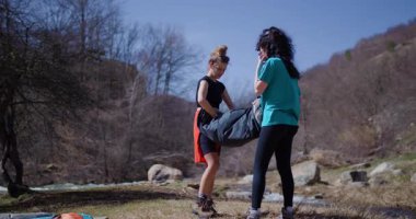 İki bayan arkadaş nehrin yanında kamp kuruyor. Rahatlatıcı bir maceraya hazırlanmak için çadırlarını ve teçhizatlarını açıyorlar..