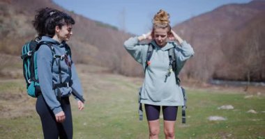 İki bayan arkadaş nehrin yakınında doğa yürüyüşü yapıyorlar. Yürüyüş planlarını tartışıyor ve güzel manzaranın tadını çıkarıyorlar..