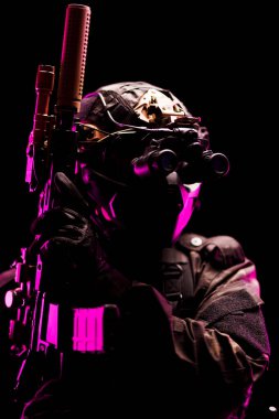 Dramatik pembe ve siyah aydınlatma altında gelişmiş silahlar ve koruyucu ekipmanlarla donatılmış bir taktik operatörünün görsel olarak çarpıcı tasviri, hazırlık, güvenlik ve