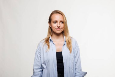 Bir iş kadını açık mavi bir gömlekle, parlak bir stüdyo arka planında profesyonel davranışını sergiliyor. Düşünceli ve dengeli görünüyor, modern girişimciliği somutlaştırıyor..