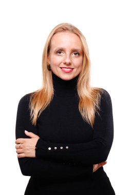 Uzun sarı saçlı, kendine güvenen bir iş kadını kollarını kavuşturmuş, siyah balıkçı yaka giyiyor. Arkaplan sade, profesyonel tavrını ve tarzını vurguluyor..