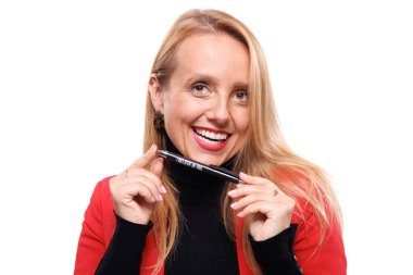 Bir iş kadını elinde kalem tutarken gülümsüyor, kendine güven ve yakınlık yayıyor. İşle ilgili bir etkinlikte profesyonelliği ve yaratıcılığı gösteren şık bir kıyafet giyiyor..