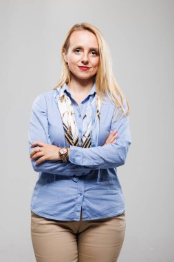 Bu kendine güvenen iş kadını kollarını kavuşturmuş açık mavi bir gömlek ve şık bir eşarp giyiyor. İfadesi kararlılığı ve odaklanmayı yansıtıyor, profesyonel bir ortam için ideal..