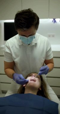 Modern bir diş kliniğinde yetenekli bir dişçinin bir hastaya tedavi sağladığı görülmektedir. Prosedür hasta rahatlığı ve profesyonel bakım üzerinde yoğunlaşıyor, gelişmiş teknikler sergileniyor.