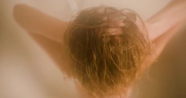 Rahatlatıcı bir duş başlığının altında saç kremiyle saçlarını pohpohlayan bir kızın keyfini çıkarın. Sıcak su, o rahat banyoda dinlenirken saç bakımını arttırıyor..