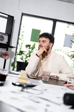 Bir iş adamı çağdaş bir ofiste bir tartışmayla meşgul olur. Kağıtlarla, içkilerle ve düşünceli bir ifadeyle bir masada otururken, diğerleri sohbete katkıda bulunuyor..