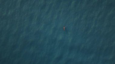 Açık mavi sularda yüzen bir kadın. Rahatlama ve dinginliğin havadan görünüşü. Seyahat, tatil ve yaşam tarzı projeleri için mükemmel..