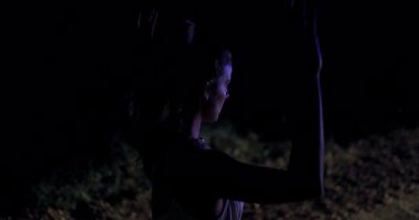 Gece geç saatlerde, polis memurları ona yaklaşırken bir kız ellerini kaldırarak korku ve belirsizlik gösterisi yapıyor. Çevre karanlık ve tenha görünüyor, gerginliği arttırıyor..