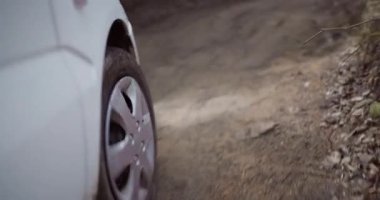 Toprak bir yolda yol alan bir SUV lastiğinin yakın görüntüsü, engebeli bir çevrede macera ve keşfi simgeliyor..