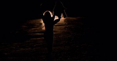 Bir kız karanlık bir ortamda güven içinde yürür, silueti bir arabanın parlayan farlarıyla güçlenir. Sahne, gecenin yalnızlığını ve yansımasını yakalar..