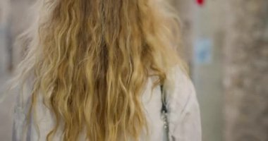 Canlı bir yerde, çarpıcı uzun saçlı bir kız zarif bir şekilde yürüyor, güzelliği canlı atmosferle harmanlıyor..